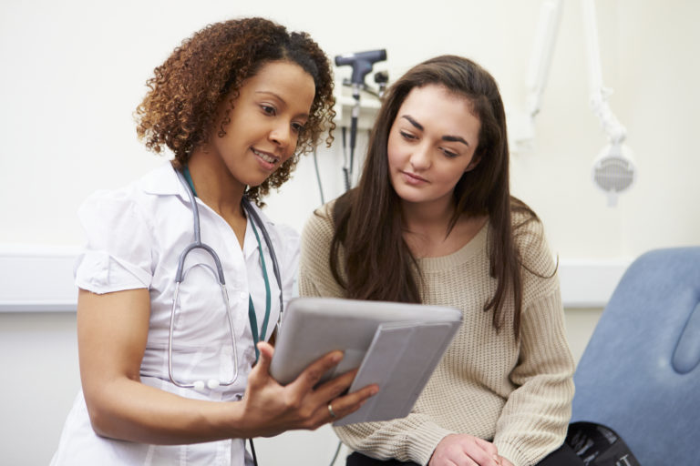 Image of doctor and patient in doctors office looking at ipad