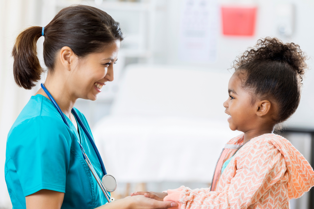 Image of doctor and child in doctors office, doctor holding childs hands