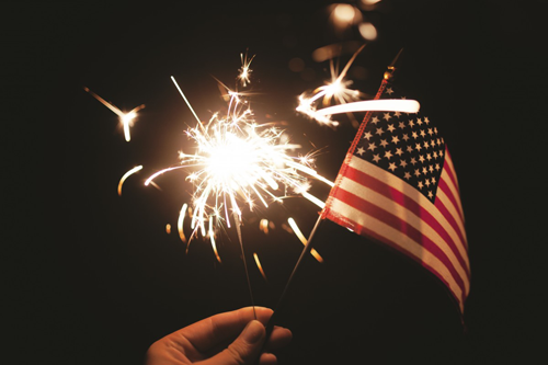 Image of a hand holding a U.S.A. flag and a Sparkler.