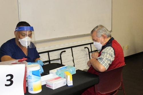 Photo of a vaccine provider and a citizen in the process of receiving the Covid 19 vaccine.