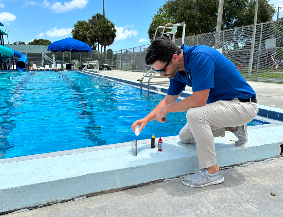 DOH employee testing water quality at public pool.