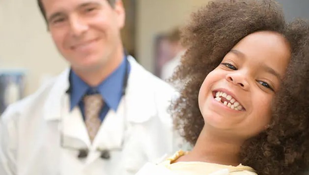 Dental Health Clinic 1 child in foreground smiling with doctor in background